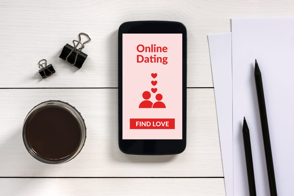 Smartphone mit Dating-App liegt auf dem Tisch, zwischen Schreibtischutensilien